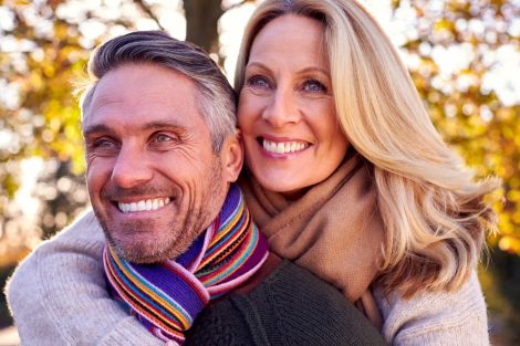 Loving Mature Woman Hugging Man From Behind As Retired Couple Walk Through Autumn Countryside